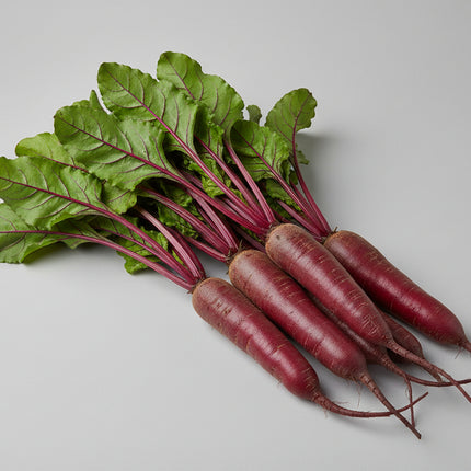 Beets with green leaves on a wooden surface