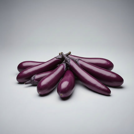 Several long, glossy purple eggplants arranged on a bed of green leaves with scattered red chili peppers.