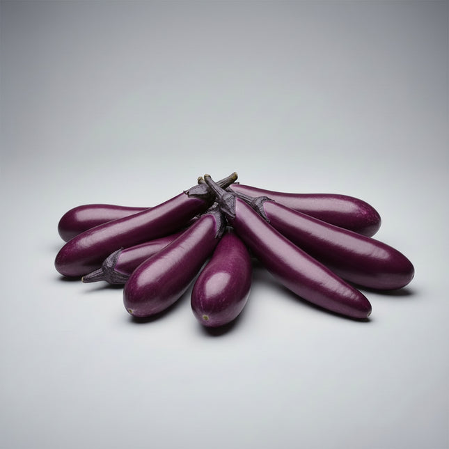 Several long, glossy purple eggplants arranged on a bed of green leaves with scattered red chili peppers.